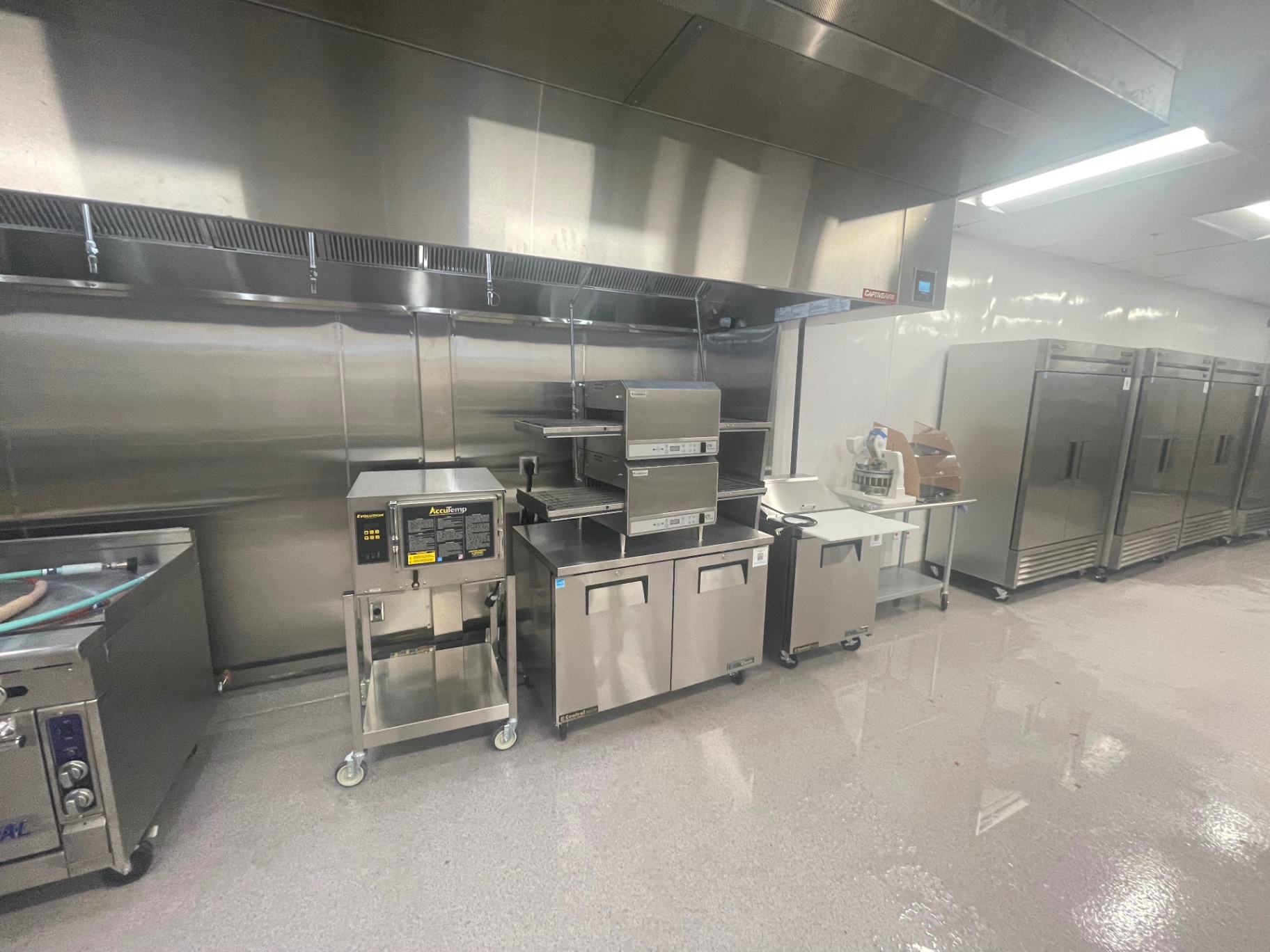 Cleaned foodservice kitchen line with stainless equipment and exhaust hood